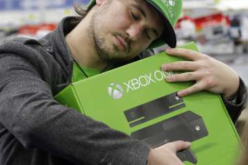 Emanuel Jumatate from Chicago, hugs his newest XBox One after he purchased it at a Best Buy on Friday, Nov. 22, 2013., in Evanston, Ill. The Xbox One, which includes an updated Kinect motion sensor, cost $500. Microsoft is billing it as an all-in-one entertainment system rather than just a gaming console. (AP Photo/Nam Y. Huh)